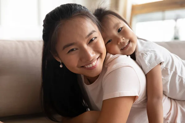 Atraktivní mladá asijská matka drží na zádech roztomilé malé dítě. — Stock fotografie