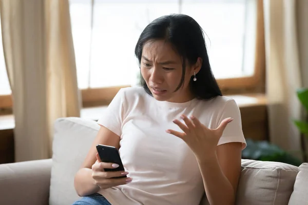 Fiatal vietnámi nő érzi bosszús nézi smartphone képernyő. — Stock Fotó