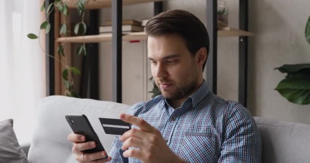 Homem feliz segurando celular usando cartão de crédito faz compra — Vídeo de Stock