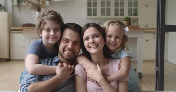 Pais felizes com filhos se unindo olhando para a câmera em casa — Vídeo de Stock