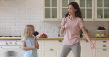 Komik kız ve anne mutfakta mutfak gereçlerinde şarkı söylüyorlar.