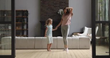 Mutlu anne ve küçük kız oturma odasında dans ediyorlar.