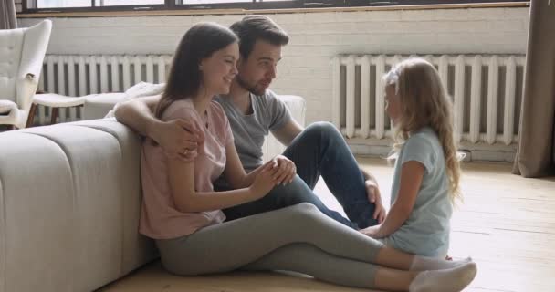 Счастливые родители и дочь разговаривают смеясь обнимаясь на полу — стоковое видео
