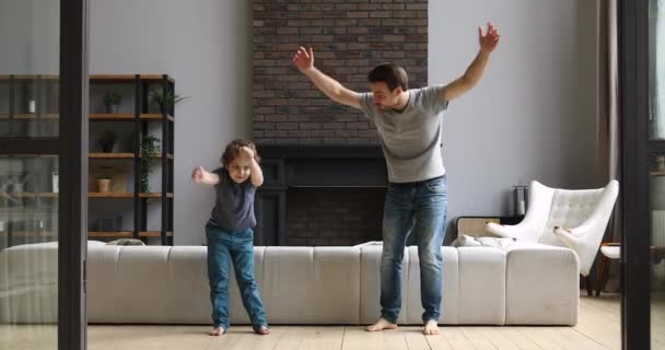 Padre activo enseñando hijo haciendo ejercicio matutino bailando en casa — Vídeo de stock
