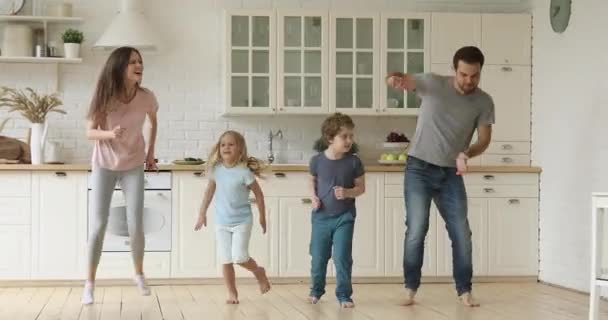 キッチンで一緒に精力的なダンスを楽しんでジャンプクレイジーアクティブな家族 — ストック動画