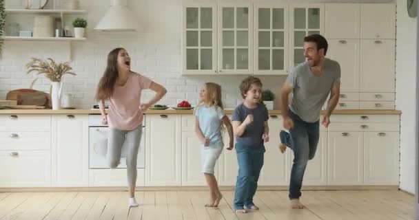 Padres activos felices y niños lindos saltando juntos en la cocina — Vídeos de Stock