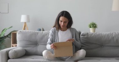 Mutlu genç bayan müşteri karton kutuyu paketten memnun olarak açıyor.