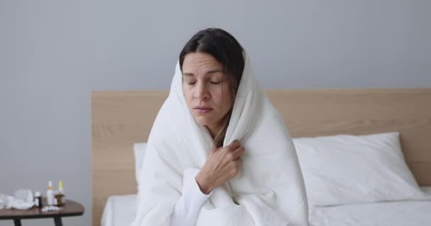 Ill young woman covered with blanket blowing nose got flu — Stock Video