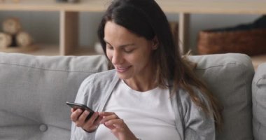 Gülümseyen genç kadın akıllı telefondaki ses asistanıyla konuşuyor.