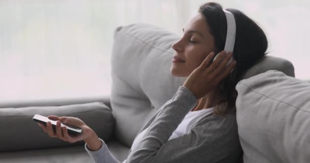Klidná dívka nosit sluchátka drží telefon relaxační poslech mobilní hudby — Stock video