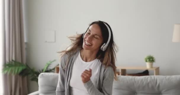 Engraçado menina feliz usar fones de ouvido sem fio pulando dançando em casa — Vídeo de Stock