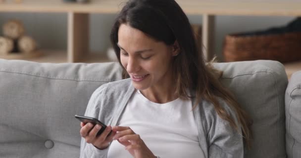 Усміхнена молода жінка розмовляє з голосовим помічником на смартфоні — стокове відео