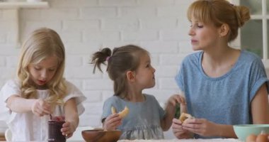 Sevimli çocuklar ve mutfakta kurabiye yiyen mutlu anneler.