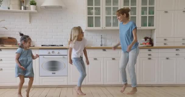 Glückliche aktive Mutter und zwei Kinder tanzen gemeinsam in der Küche — Stockvideo
