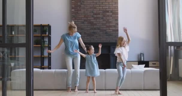 Šťastná matka a dvě dcery tančí spolu v obýváku — Stock video