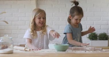 İki tatlı kız kardeş mutfakta hamur pişirme oyunu oynuyorlar.