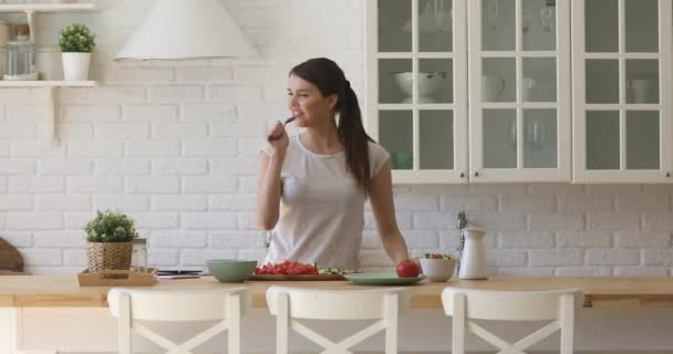 Щаслива жінка тримає ложку мікрофона співає танці, готуючи на кухні — стокове відео
