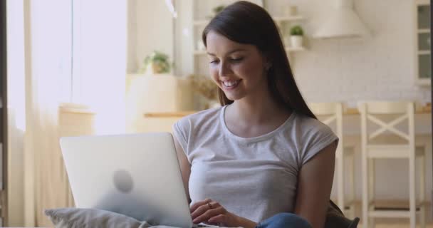 Souriant jeune femme en utilisant ordinateur portable portable portable assis à la maison — Video