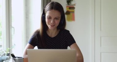 Kadın kulaklık takıyor. Öğretmen ile konuşuyor. Video çağrısı ile uzaktan çalışıyor.