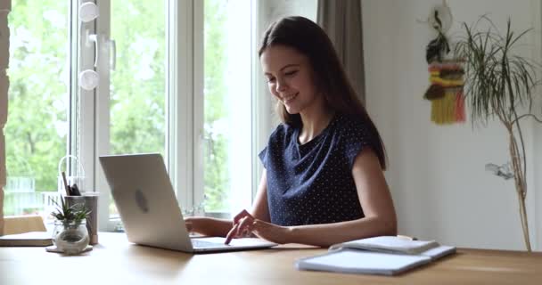 Женщина, сидящая за столом, печатая электронную почту с помощью ноутбука чувствует удовлетворение — стоковое видео