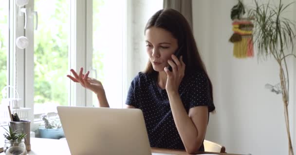 Женщина, сидящая за столом и разговаривающая с другом по телефону — стоковое видео