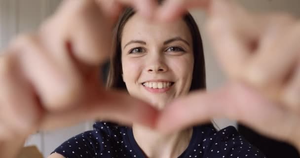 Chica hace con los dedos corazón mirando a la cámara se siente feliz — Vídeos de Stock