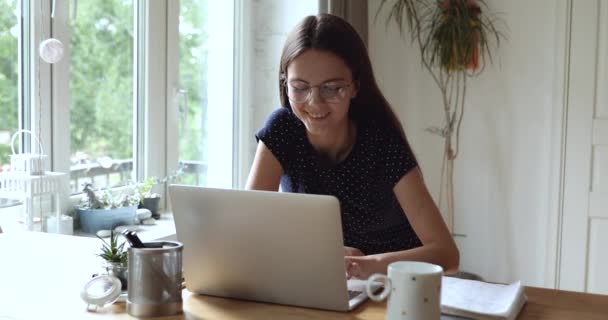 Młoda atrakcyjna uśmiechnięta kobieta nosić okulary smsowanie wiadomości używać laptopa — Wideo stockowe