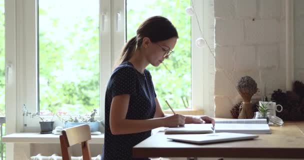 Női fordító fordítja szöveg dolgozik ül asztalnál otthon — Stock videók
