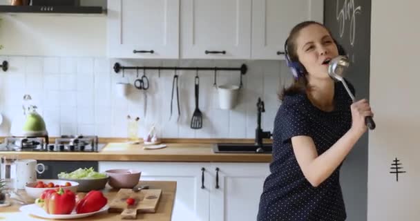 W kuchni tańcząca kobieta śpiewa piosenkę używając chochli jak mikrofonu — Wideo stockowe