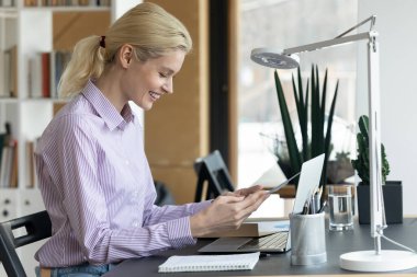 Gülümseyen genç kadın, kağıt mektup okurken heyecanlanıyor.