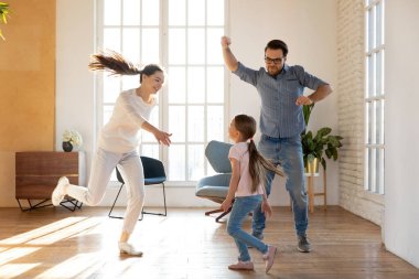 Heyecanlı evli çift ve küçük kızı oturma odasında dans ediyor.