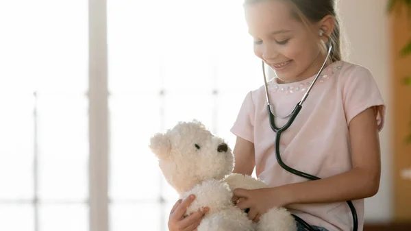 Smiling little girl playing with fluffy toy and stethoscope