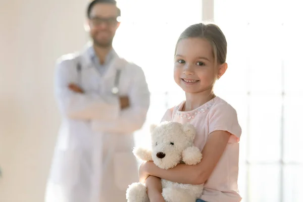 Hoofd schot portret glimlachend klein meisje met speelgoed in kliniek — Stockfoto