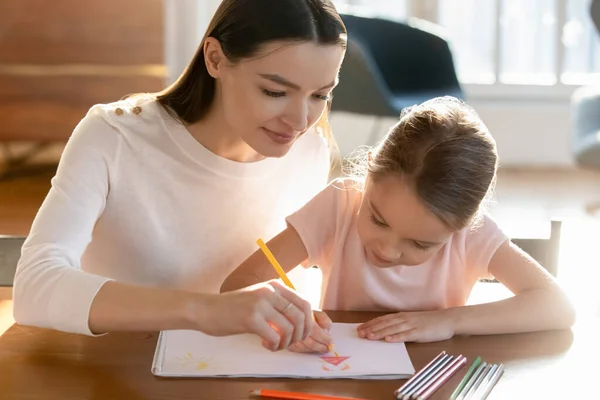 Madre cariñosa enseñando a su hija a dibujar lápices de colores — Foto de Stock