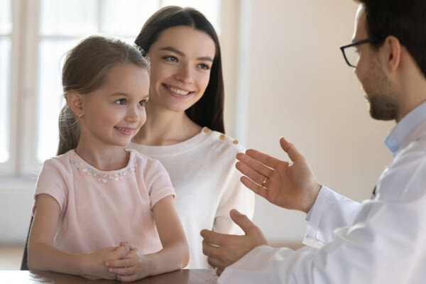 Педиатр консультирует улыбающуюся мать с маленькой дочерью на встрече
