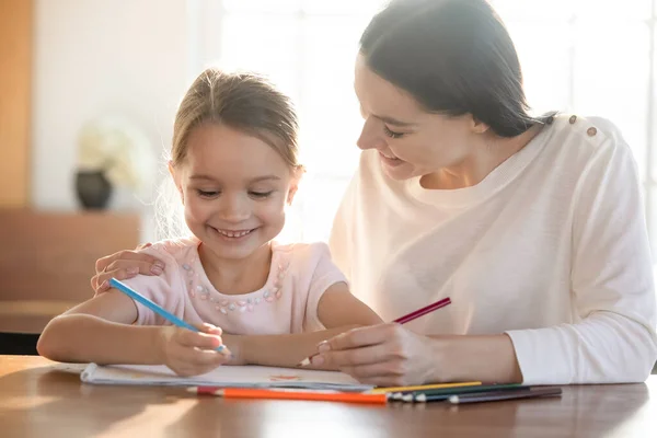 Madre sonriente cariñosa e hija pequeña dibujando lápices de colores —  Fotos de Stock