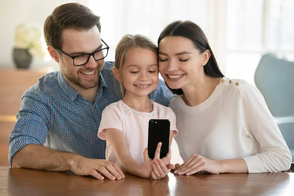 Leende liten flicka med mor och far som tar selfie — Stockfoto