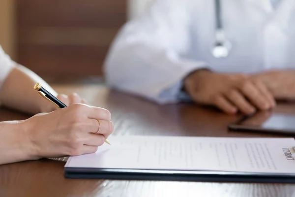 Close up female patient signing contract with therapist in clinic — Stock Photo, Image