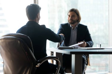 Buluşmada ortaklık kuran gülümseyen iki genç iş adamı.