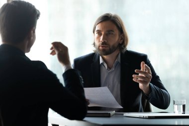 Ciddi genç yönetici ortakla sözleşmeyi tartışıyor.