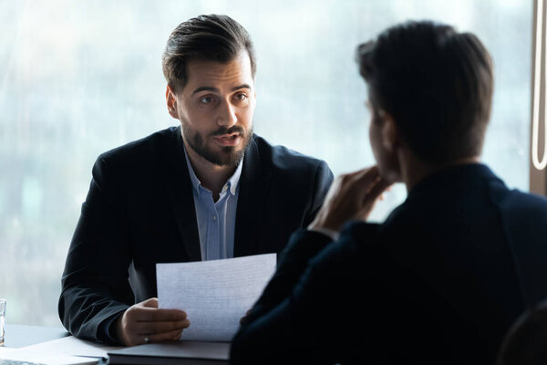 Serious young businessman holding job interview with applicant.