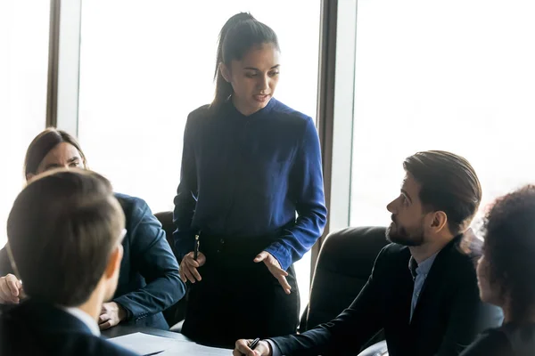 Joven empresaria seria explicando estrategia de desarrollo a colegas enfocados . —  Fotos de Stock