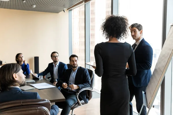 Indietro vista posteriore giovane afroamericano altoparlante femminile in piedi vicino flipchart. — Foto Stock