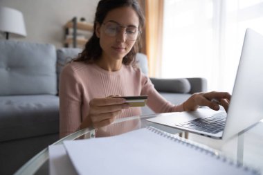 Genç beyaz kadın kredi kartıyla online alışveriş yapıyor.