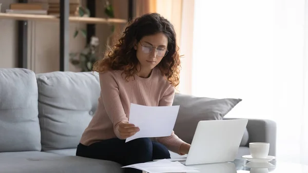 Jeune femme caucasienne travail sur ordinateur portable compte tenu de la paperasserie — Photo