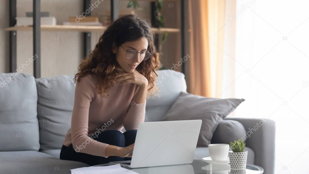 Young Caucasian woman in glasses work on laptop at home