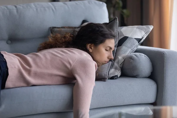 Κουρασμένη νεαρή γυναίκα κοιμάται στον καναπέ στο σπίτι — Φωτογραφία Αρχείου