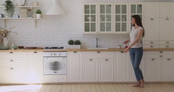 Glædelig sorgløs aktiv pige danser alene i moderne køkken interiør – Stock-video