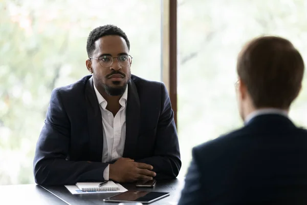 African businessman listens Caucasian partner during formal meeting in office — Stock Photo, Image