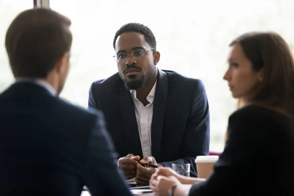 Серйозний африканський бізнесмен слухає спікера під час групової зустрічі в залі засідань — стокове фото
